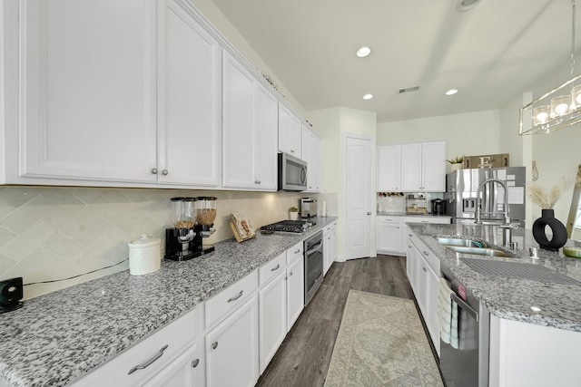 2810 Parkside Village Ln, Pearland, TX 77581 - kitchen featuring stainless steel appliances, white cabinetry, decorative backsplash, light stone countertops, and dark wood-style floors