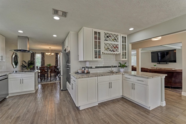 24203 Creekview Dr, Spring, TX 77389 - kitchen featuring wall chimney exhaust hood, light wood-style flooring, a peninsula, white cabinetry, and recessed lighting