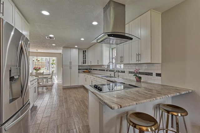 24203 Creekview Dr, Spring, TX 77389 - kitchen with stainless steel fridge, island range hood, black electric cooktop, a peninsula, and recessed lighting