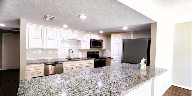 14777 Wunderlich Dr Unit 605, Houston, TX 77069 - kitchen featuring appliances with stainless steel finishes, dark wood-style flooring, a peninsula, stone counters, and a textured ceiling