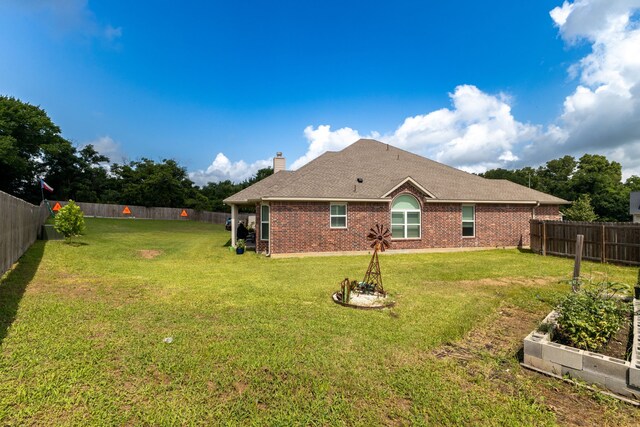 1803 Twin Oaks Cir, Brenham, TX 77833 - rear view of house featuring a fenced backyard, a chimney, brick siding, and a shingled roof