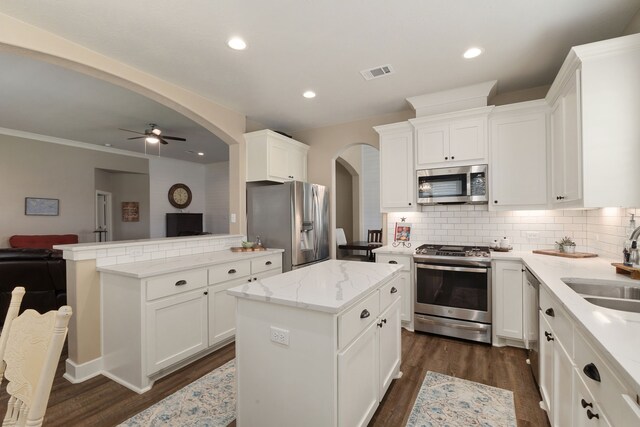1803 Twin Oaks Cir, Brenham, TX 77833 - kitchen with appliances with stainless steel finishes, arched walkways, a center island, dark wood-type flooring, and tasteful backsplash