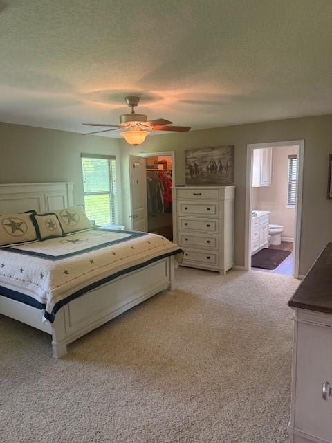 240 Rosalie St, Shepherd, TX 77371 - bedroom with light colored carpet, a walk in closet, a textured ceiling, ceiling fan, and connected bathroom