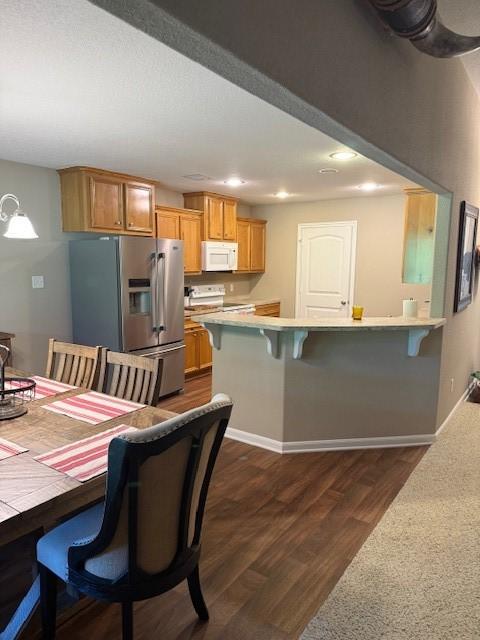 240 Rosalie St, Shepherd, TX 77371 - kitchen featuring white microwave, stainless steel fridge with ice dispenser, electric range oven, light countertops, and a kitchen bar