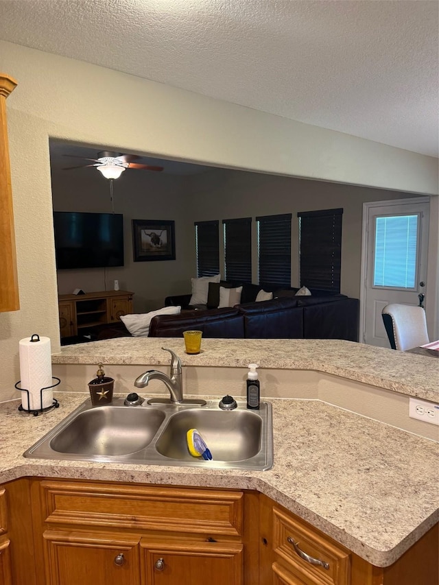 240 Rosalie St, Shepherd, TX 77371 - kitchen with open floor plan, light countertops, brown cabinets, a ceiling fan, and a textured ceiling