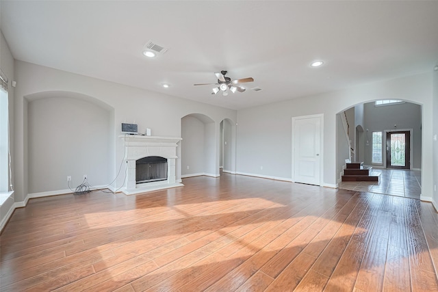 11107 Camino Oaks Dr, Houston, TX 77064 - unfurnished living room with a ceiling fan, light wood finished floors, a tile fireplace, arched walkways, and recessed lighting