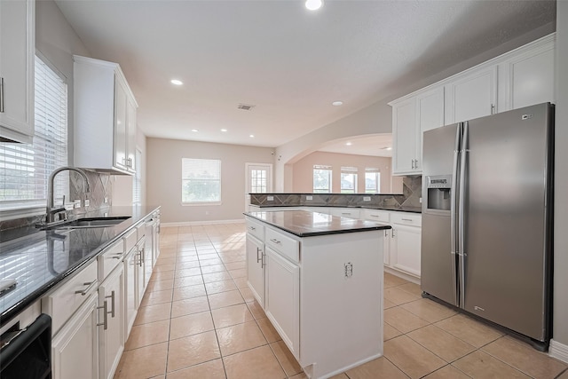 11107 Camino Oaks Dr, Houston, TX 77064 - kitchen with stainless steel fridge, decorative backsplash, white cabinetry, arched walkways, and recessed lighting