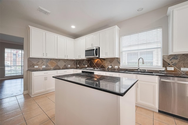 11107 Camino Oaks Dr, Houston, TX 77064 - kitchen featuring stainless steel appliances, white cabinets, backsplash, a center island, and light tile patterned floors