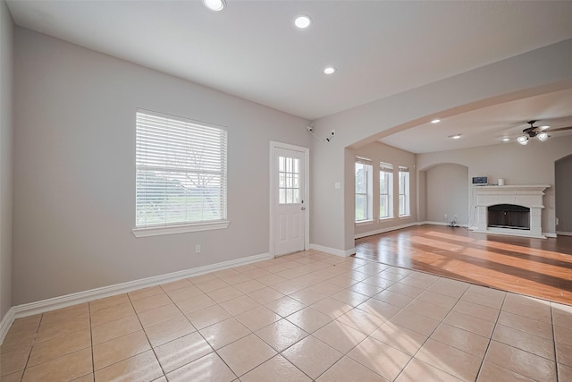 11107 Camino Oaks Dr, Houston, TX 77064 - unfurnished living room featuring light tile patterned floors, ceiling fan, recessed lighting, a fireplace, and arched walkways