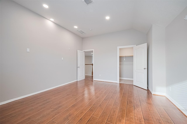 11107 Camino Oaks Dr, Houston, TX 77064 - unfurnished bedroom with light wood finished floors, a walk in closet, vaulted ceiling, and recessed lighting
