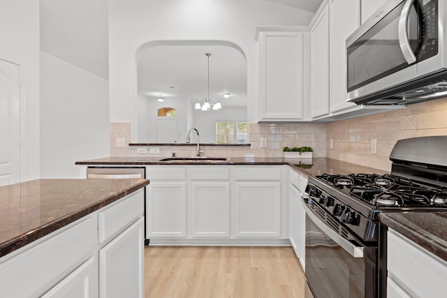 506 Mornington Ln, Katy, TX 77494 - kitchen with stainless steel microwave, gas stove, dark stone counters, decorative backsplash, and a chandelier