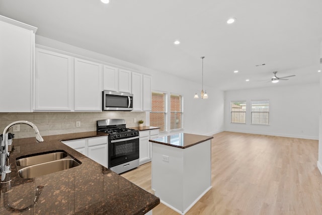 506 Mornington Ln, Katy, TX 77494 - kitchen featuring stainless steel microwave, gas stove, backsplash, white cabinets, and a kitchen island