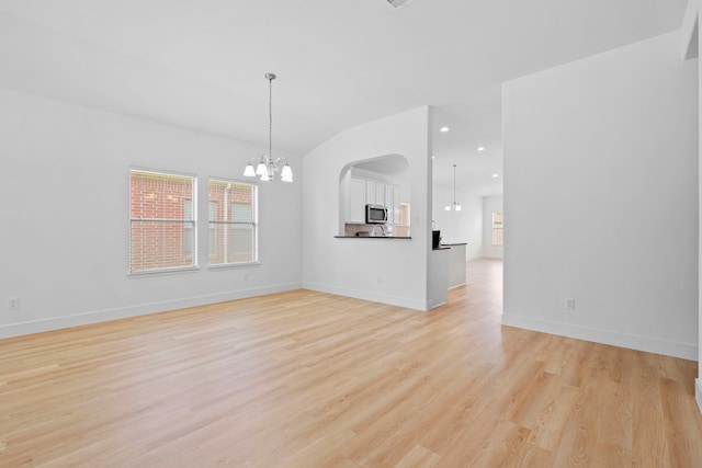 506 Mornington Ln, Katy, TX 77494 - unfurnished living room with a chandelier, light wood-type flooring, vaulted ceiling, arched walkways, and recessed lighting