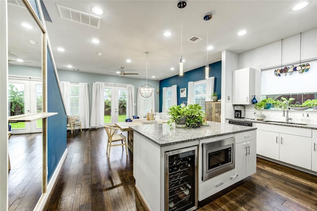 2013 Schweikhardt St, Houston, TX 77020 - kitchen featuring wine cooler, stainless steel microwave, french doors, a center island, and white cabinets