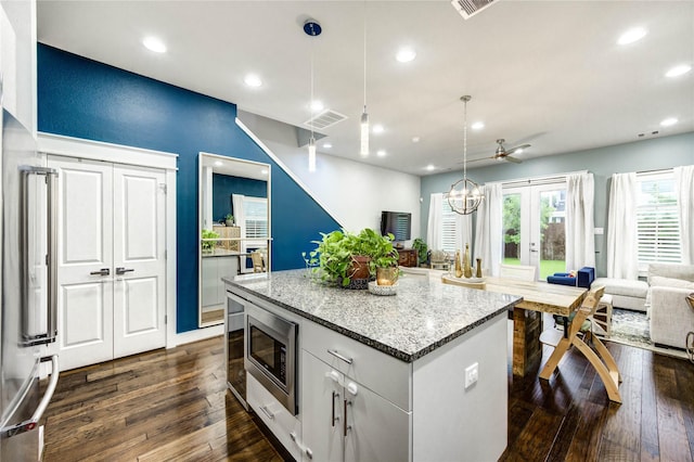 2013 Schweikhardt St, Houston, TX 77020 - kitchen featuring stainless steel microwave, a center island, dark wood-style floors, open floor plan, and light stone counters