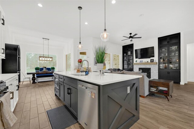 960 Rd 6609, Dayton, TX 77535 - kitchen with dishwasher, light countertops, a ceiling fan, a fireplace, and light wood-style flooring