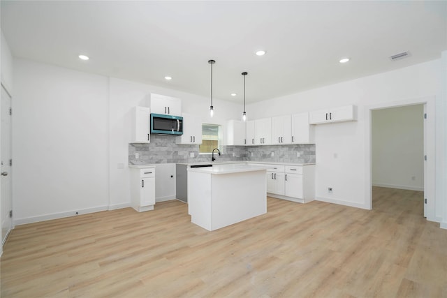 7504 Laura Koppe Rd C/D, Unit C/D Houston, TX 77028 - kitchen with stainless steel microwave, backsplash, white cabinetry, recessed lighting, and a center island