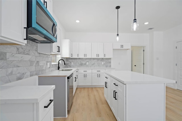 7504 Laura Koppe Rd C/D, Unit C/D Houston, TX 77028 - kitchen featuring appliances with stainless steel finishes, light wood-style floors, backsplash, light countertops, and hanging light fixtures