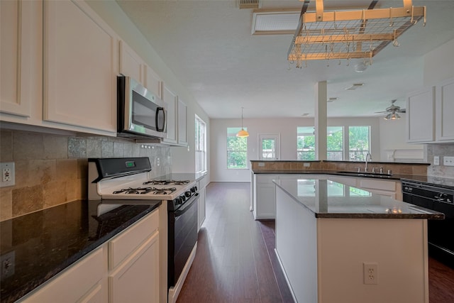 619 Bending Bough Dr, Spring, TX 77388 - kitchen featuring gas range, stainless steel microwave, dark wood-style flooring, black dishwasher, and a peninsula