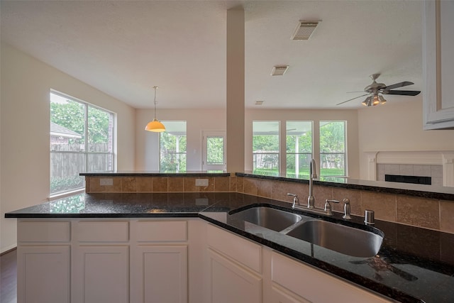 619 Bending Bough Dr, Spring, TX 77388 - kitchen with white cabinets, dark stone counters, decorative light fixtures, a fireplace, and a ceiling fan