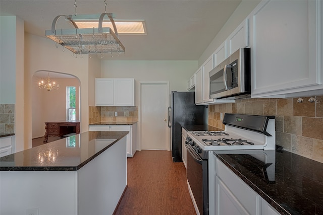 619 Bending Bough Dr, Spring, TX 77388 - kitchen featuring stainless steel microwave, white range with gas stovetop, white cabinetry, arched walkways, and dark wood-type flooring