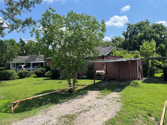 10113 Teneha Dr, Houston, TX 77033 - view of green lawn with dirt driveway and a carport