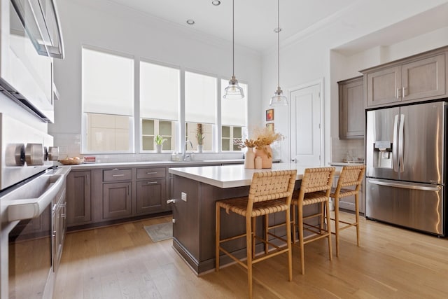 6006 Matthew Oaks Pl, Houston, TX 77007 - kitchen featuring stainless steel appliances, ornamental molding, backsplash, light countertops, and light wood-type flooring