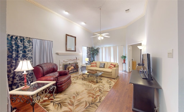 3011 Flower Field Ln, Pearland, TX 77584 - living room featuring ornamental molding, wood finished floors, a towering ceiling, ceiling fan, and a tile fireplace