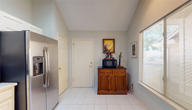 3011 Flower Field Ln, Pearland, TX 77584 - kitchen with stainless steel refrigerator with ice dispenser, black microwave, lofted ceiling, light tile patterned flooring, and white cabinetry