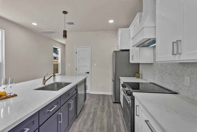 2413 Harlem St, Houston, TX 77020 - kitchen featuring stainless steel appliances, custom exhaust hood, white cabinetry, light wood-type flooring, and decorative backsplash