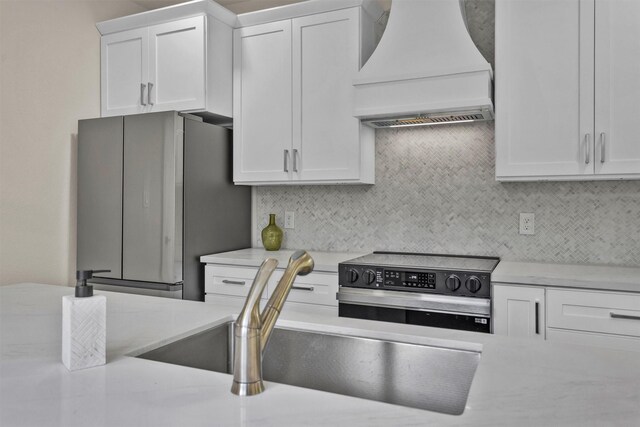 2413 Harlem St, Houston, TX 77020 - kitchen with custom exhaust hood, freestanding refrigerator, stainless steel range with electric cooktop, white cabinetry, and tasteful backsplash