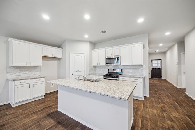 12303 Trumpetfish Ct, Conroe, TX 77304 - kitchen featuring appliances with stainless steel finishes, backsplash, white cabinets, dark wood finished floors, and a center island with sink