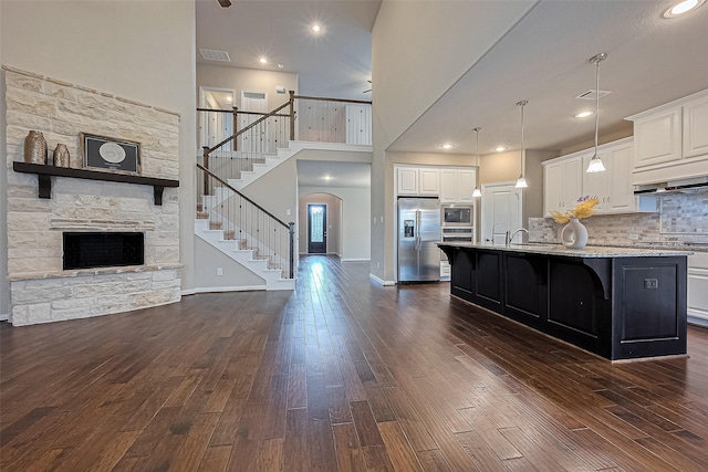 6518 Nicholas Trl, Sugar Land, TX 77479 - kitchen featuring appliances with stainless steel finishes, open floor plan, a kitchen breakfast bar, white cabinetry, and a high ceiling