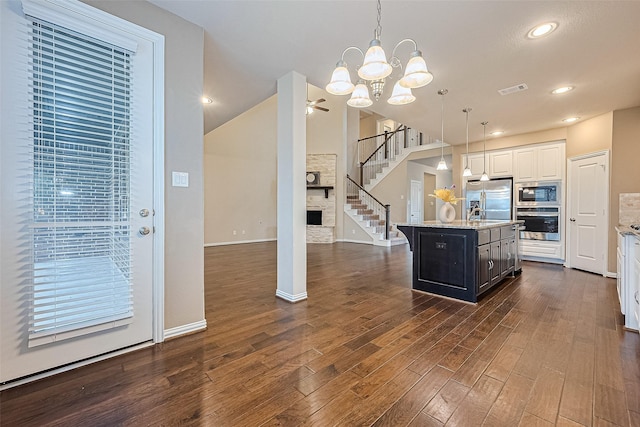 6518 Nicholas Trl, Sugar Land, TX 77479 - kitchen featuring appliances with stainless steel finishes, a kitchen island with sink, dark wood-style flooring, hanging light fixtures, and a chandelier