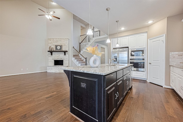 6518 Nicholas Trl, Sugar Land, TX 77479 - kitchen featuring stainless steel appliances, white cabinetry, dark wood-type flooring, and high vaulted ceiling