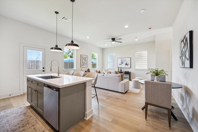 5256 Texas St, Houston, TX 77011 - kitchen featuring stainless steel dishwasher, light wood finished floors, ceiling fan, an island with sink, and decorative light fixtures