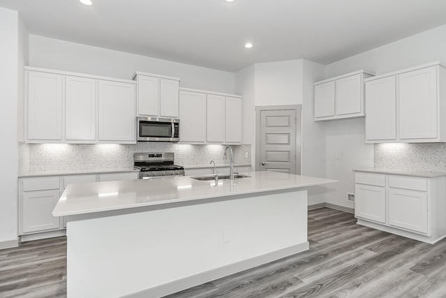 6222 Pelican Ridge Way, League City, TX 77573 - kitchen with stainless steel appliances, a kitchen island with sink, white cabinetry, light countertops, and recessed lighting