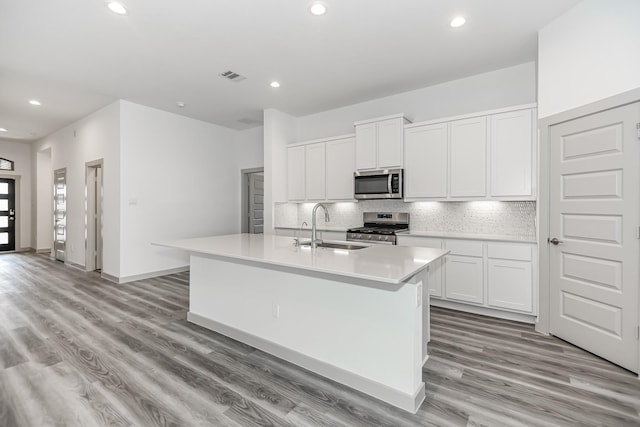 6222 Pelican Ridge Way, League City, TX 77573 - kitchen featuring stainless steel appliances, decorative backsplash, recessed lighting, light wood-style floors, and white cabinetry