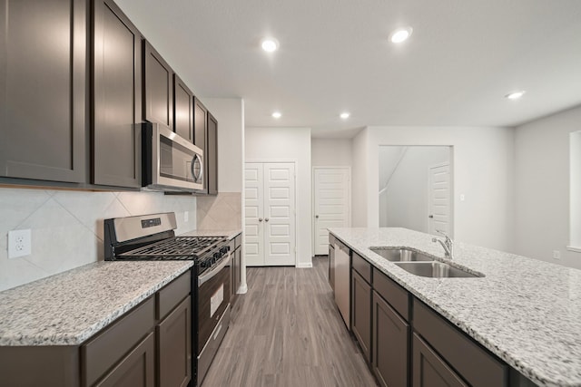 13200 Musky Dr, Conroe, TX 77384 - kitchen with stainless steel appliances, wood finished floors, backsplash, recessed lighting, and light stone countertops