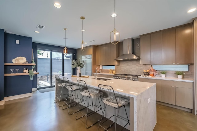 1906 Park St, Houston, TX 77019 - kitchen with wall chimney range hood, stainless steel built in refrigerator, concrete flooring, decorative backsplash, and a breakfast bar area