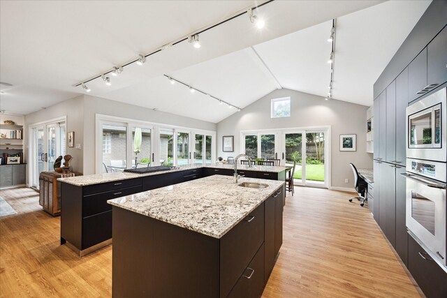 5171 Jason St, Houston, TX 77096 - kitchen featuring rail lighting, a kitchen island with sink, stainless steel appliances, french doors, and vaulted ceiling