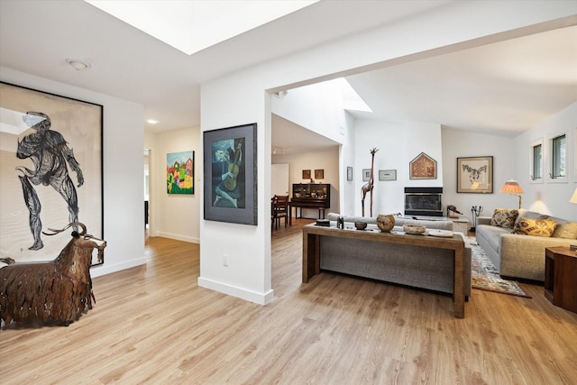 5171 Jason St, Houston, TX 77096 - living area with light wood-type flooring, vaulted ceiling, a glass covered fireplace, and a skylight