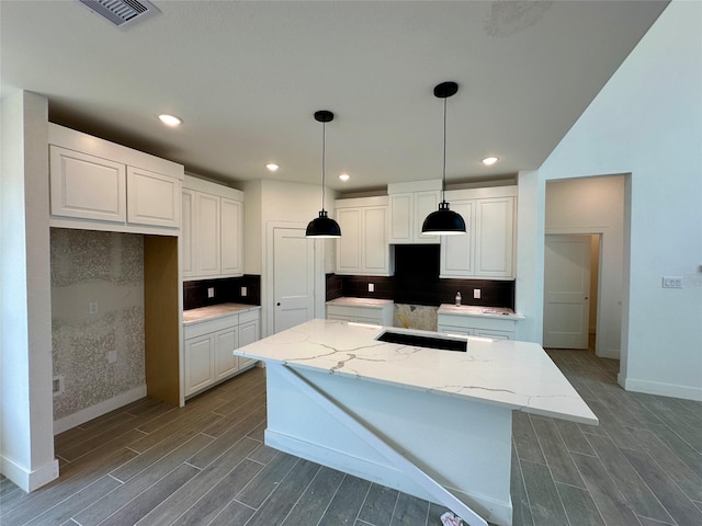 13085 Brookwood Bend Ln, Conroe, TX 77302 - kitchen featuring wood tiled floors, a kitchen island, decorative backsplash, hanging light fixtures, and recessed lighting
