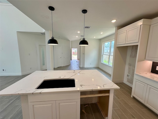13085 Brookwood Bend Ln, Conroe, TX 77302 - kitchen with wood tiled floors, stovetop, white cabinets, light stone counters, and decorative light fixtures