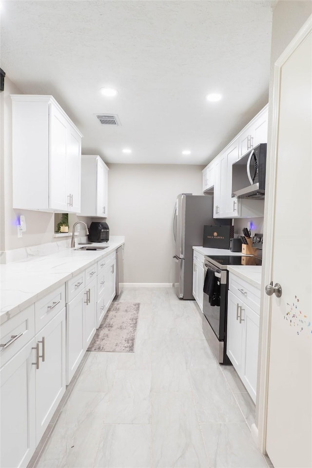 9106 Gustine Ln, Houston, TX 77031 - kitchen featuring stainless steel appliances, light marble finish floors, white cabinets, recessed lighting, and light stone countertops