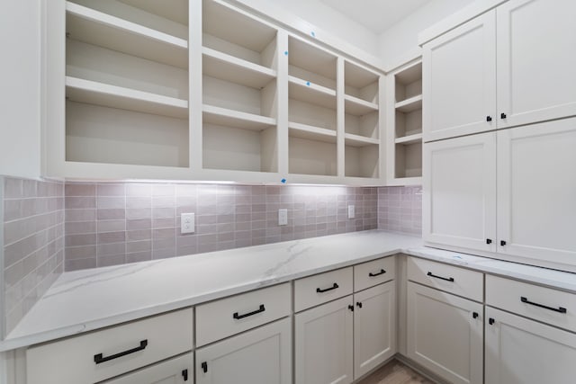 12814 Forest Garden Ct, Conroe, TX 77302 - kitchen featuring open shelves, tasteful backsplash, light stone countertops, and white cabinetry