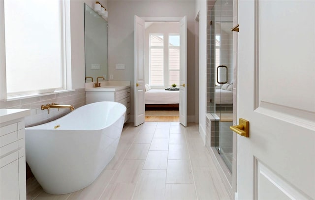 2611 Sherwin St, Houston, TX 77007 - bathroom with a shower stall, vanity, a soaking tub, tile patterned floors, and tile walls