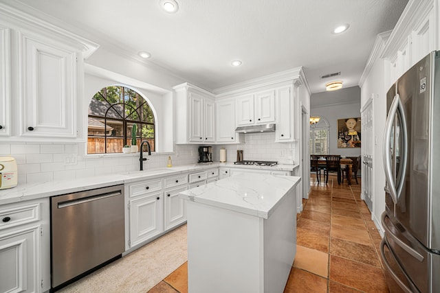 12927 Finch Brook Dr, Cypress, TX 77429 - kitchen featuring appliances with stainless steel finishes, white cabinets, decorative backsplash, a kitchen island, and light stone counters