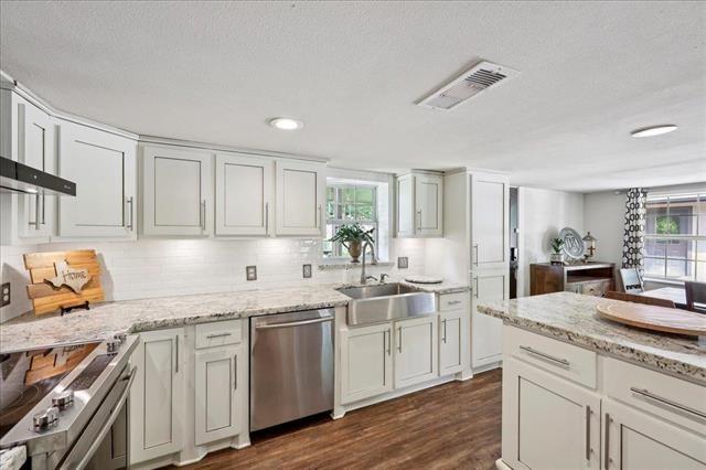 3231 Charles Ave, Groves, TX 77619 - kitchen with stainless steel appliances, dark wood finished floors, tasteful backsplash, and white cabinets