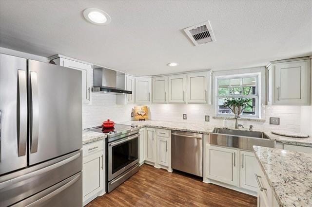 3231 Charles Ave, Groves, TX 77619 - kitchen with appliances with stainless steel finishes, wall chimney exhaust hood, decorative backsplash, light stone counters, and recessed lighting